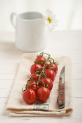 Cherry tomatoes on a white table, white flower in background
