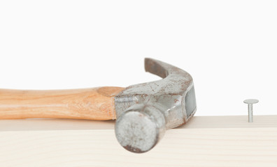 A hammer and a drived nail on a wooden board