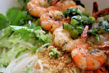 Grilled shrimp on bed of rice noodles and greens.
