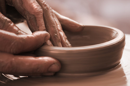 human hands moulding with the clay on a potter`s wheel close up.