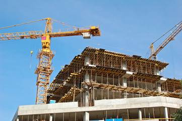 Building crane and building under construction against blue sky