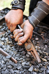 Detail of dirty hands holding pliers - blacksmith