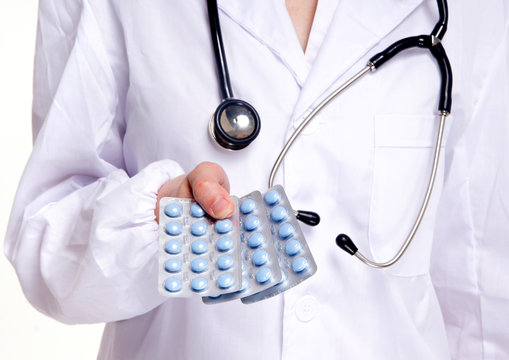 Close-up of a doctor showing three packs of blue pills