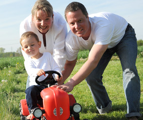Junge Eltern und Sohn mit rotem Traktor