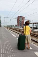 Young boy with luggage waiting for train