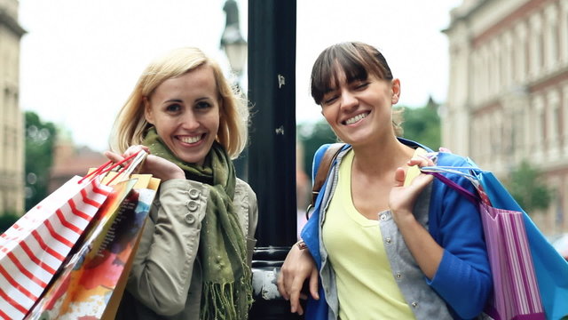two happy female friends with shopping bags in the city