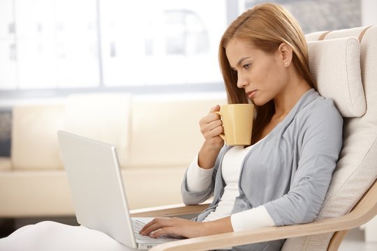 Young woman with laptop drinking tea