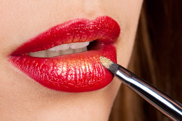 Closeup of lips with red lipstick, applying golden powder
