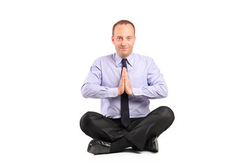 A businessman doing yoga exercise seated on a floor