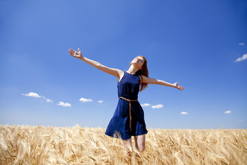 Redhead girl at wheat field in summer day. © Masson