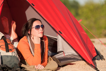 Camping happy woman in tent on beach sunset