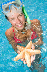 Snorkel girl with starfish in blue water
