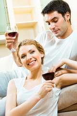 Young amorous couple celebrating with redwine at home