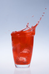 red fruity juice water splash coming out of a glass