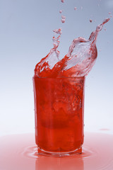 red fruity juice water splash coming out of a glass