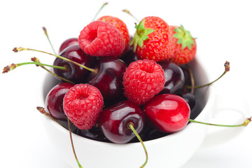 raspberries, strawberries and cherries in a bowl isolated on whi