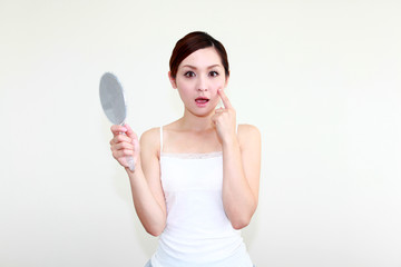 手鏡を持ち驚いた表情の女性