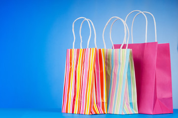 Colourful paper shopping bags against gradient background