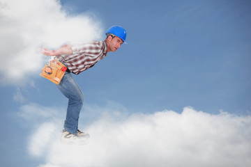 Photomontage of a young workman walking on the clouds