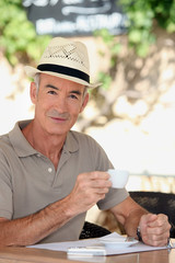 65 years old man wearing a straw hat and drinking a tea