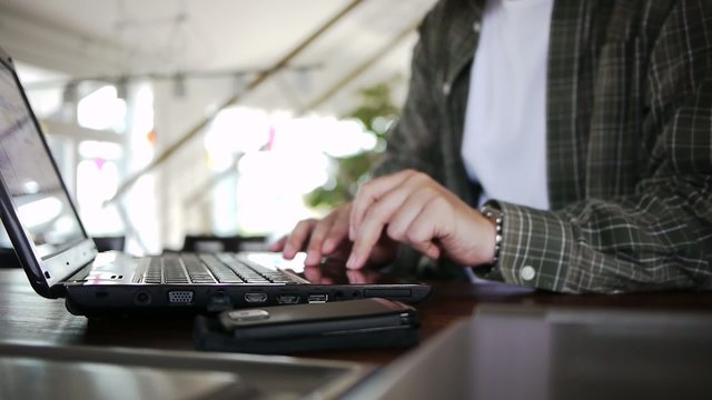 Male works on a notebook on a wooden table
