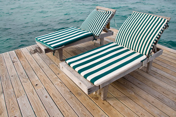 Fototapeta na wymiar Two Beach Chairs on a Dock Overlooking the Ocean