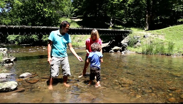Family playing in river with peebles