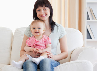 Beautiful woman holding her baby in her arms while sitting on a