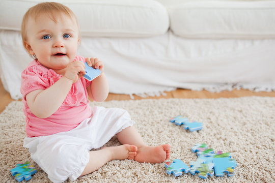 Cute Blond Baby Playing With Puzzle Pieces While Sitting On A Ca