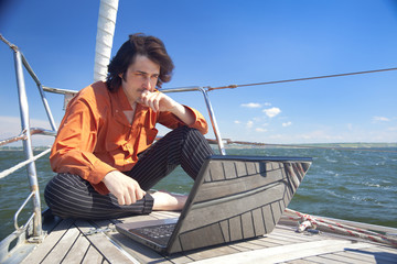 Businessman with laptop on sailboat