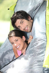 Young couple peeking out of their tent