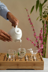 Pouring chinese green tea into glass teapot