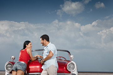 man and beautiful woman leaning on cabriolet car