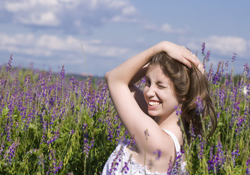 Улыбающая юная  брюнетка в поле среди цветов