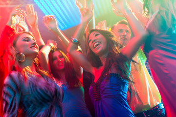 Party people dancing in disco or club