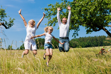 Glückliche Familie im Freien springt hoch