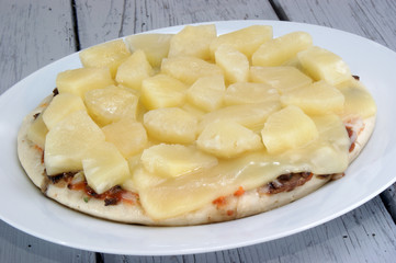 Pizza mit Käse und Ananas auf einem weißen Teller