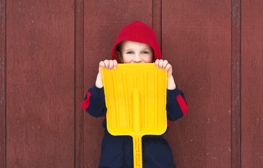Young boy hides behind toy shovel