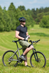 Obraz premium Sportive man mountain biking relax sunny meadows