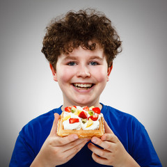 Boy eating cake with cream and fruits