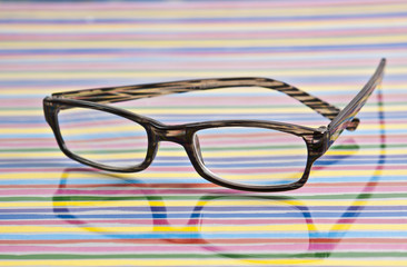 liegende Brille auf Untergund mit bunten Streifen