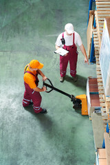 Warehouse workers with fork pallet truck stacker