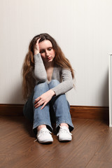 Depressed and alone a teenage girl sits on floor