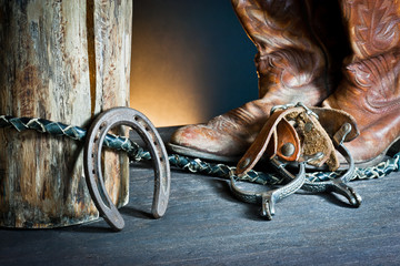 Cowboy boots,horseshoe,whip and spurs on wood