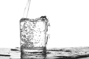 Вода льется в переполненный стеклянный стакан