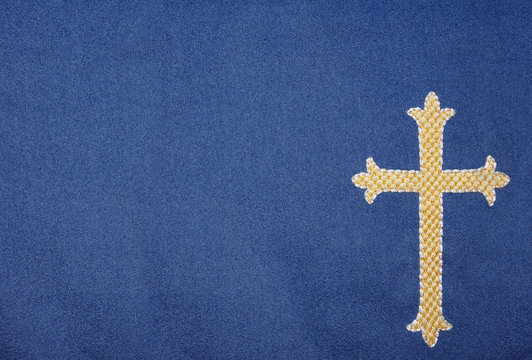 Detailed image of embroidered gold cross on blue velvet backgrou
