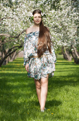 Naklejka na ściany i meble The long-haired girl against blossoming apple-trees.