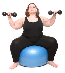 Shot of a overweight young woman with blue ball and dumbbells..