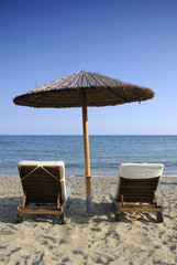 Beach umbrella and two chairs over the sea