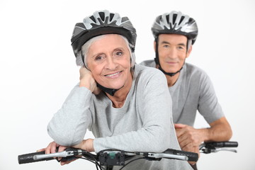 An elderly couple riding their bikes together